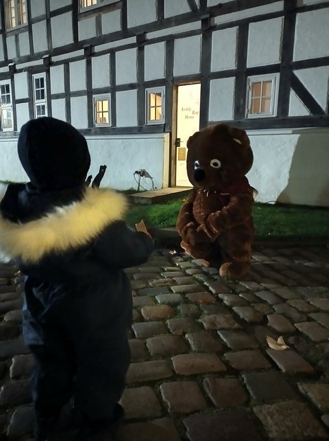 Überlebensgroßer Teddybär vor dem Teddybär-Haus im Stadtmuseum. Im Vordergrund ist ein Kind von hinten zu sehen.
