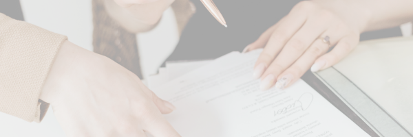 Drei Hände, eine Hand hält einen Kugelschreiber und ist kurz davor einen Arbeitsvertrag zu unterschreiben